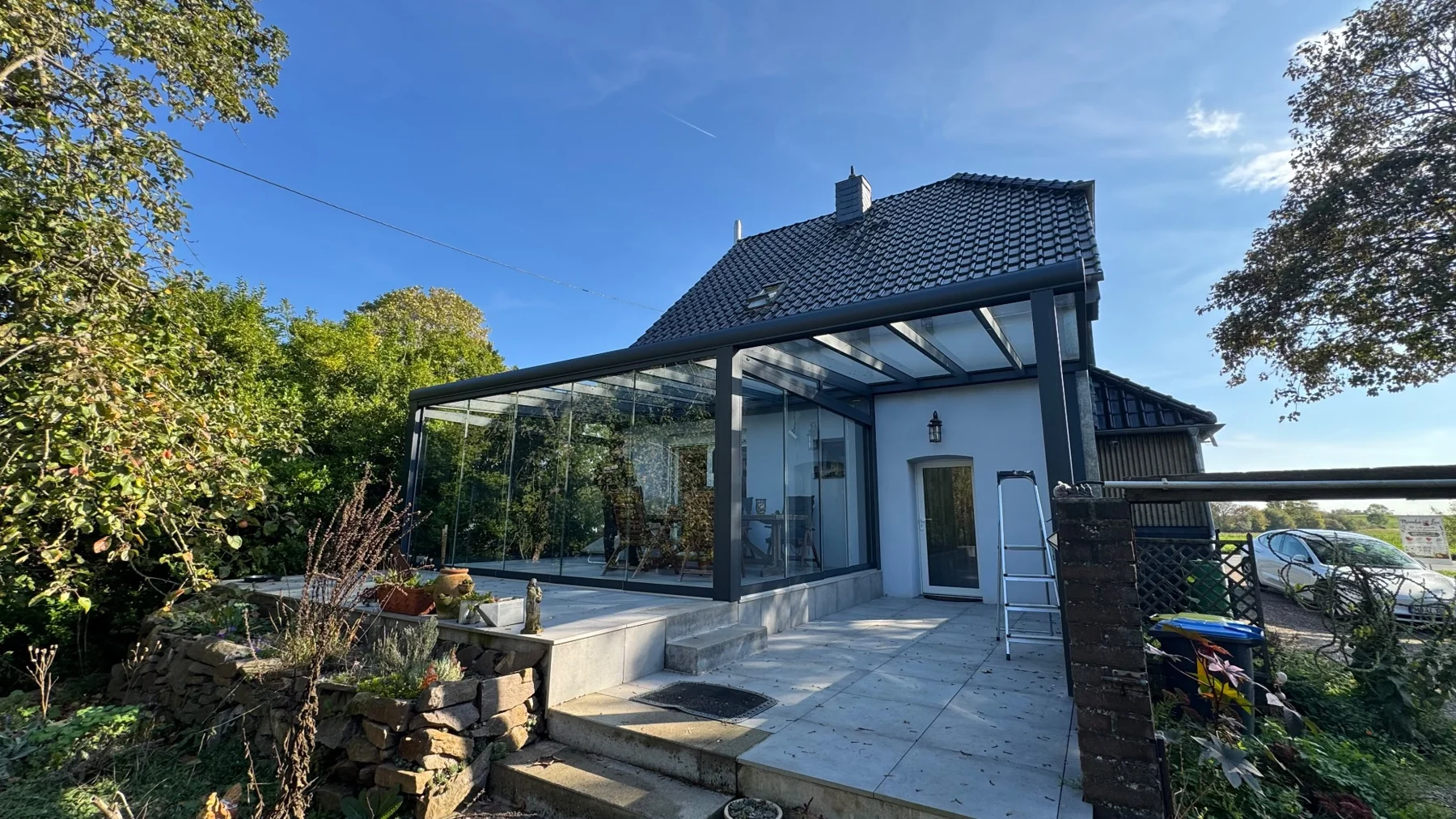 Glasüberdachung in Kamp-Lintfort mit offenem Terrassenbereich und einem durch Glasschiebewände geschlossenen Teil