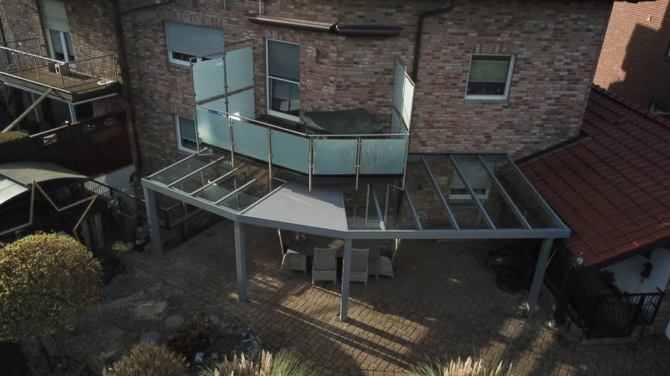 Terrassenüberdachung in Sonderform entlang einer geknickten Hauswand in Oberhausen, mit Glas und Aluminiumlamellen
